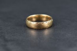 A 9ct gold wedding band, having decorative engraving to edges, ring size U, 7.2g
