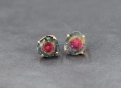 A pair of watermelon tourmaline stud earrings, the tricolour rough cut pieces in yellow metal claw