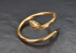 A 9ct gold flexible snake bangle with ruby set eyes and decorative engraving to the head and tail