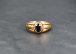 A yellow metal band ring stamped 9K having a central oval sapphire with pairs of diamond chips to
