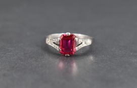 A synthetic ruby and diamond ring, the emerald cut ruby measuring approximately 1ct in a claw set