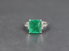 An emerald and diamond ring, the central emerald cut emerald measuring approximately 9.1mm x 8.1mm x