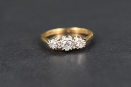 A diamond three stone ring, the central round cut diamond flanked by two smaller round cut diamonds,