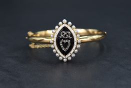 A Victorian diamond set yellow metal mourning bangle having a black and white enamelled plaque