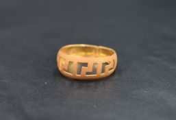 An artisan high carat gold band (tests as 18-22ct) having a pierced meander style design and matt