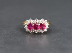 A ruby and diamond cluster ring, the three oval cut rubies measuring approximately 0.20 each with an