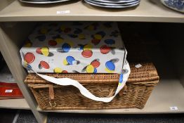 A wicker picnic basket (no contents) and a retro picnic bag with melamine plates, cups and flask.