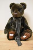 A Charlie Bear teddy bear, having a long pile plush covered body, jointed limbs, wearing a green