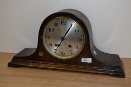 An early 20th Century stained oak mantel clock of Napoleon hat form, having a silvered arabic dial