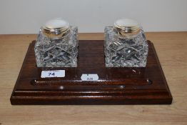 An early 20th Century mahogany inkwell stand of rectangular form with two cut glass inkwells,