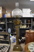 An ornate brass oil lamp having stepped base, fluted column and a decorative reservoir. Completed