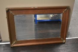 A large copper and brass wall mirror having bevelled glass, measuring 96cm x 66cm.