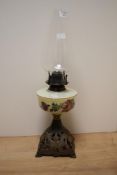 An early 20th Century oil lamp, the glass chimney above a foliate hand painted milk glass