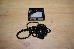 A black carved beaded necklace having round and oval beads with acorn motif beads with a matching