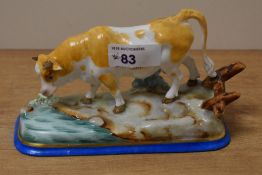 A Continental porcelain cow study, modelled in a naturalistic setting and hand decorated in