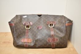 A stitched brown leather hold all in the manner of Louis Vutton, having usual repeating pattern.