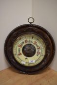 An early 20th C circular walnut barometer with foliate carved detailing.