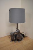 A contemporary table lamp incorporating a pair of otters in silvered finish.