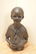 An attractive cast-resin half length bust of a young smiling boy holding a chicken 35cm having the