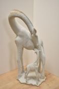 An attractive and unusual African stipple-carved yellow granite study of a giraffe cow tending to