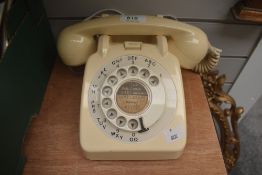 An early to mid-20th Century bakelite rotary dial telephone in cream, measuring 12cm high