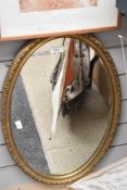 An oval gilt framed mirror.