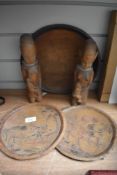 Three carved plaques having traditional scenes of people and animals and two carved women holding