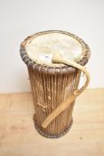 An African talking drum with beater, of typical hour glass form, measuring 46cm tall