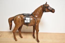 In the manner of Liberty & Co, a stained leather covered horse figure with saddle, 31.5cm, some