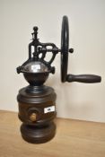 A 20th century manually operated coffee grinder, the cast metal mechanism with large wheel over