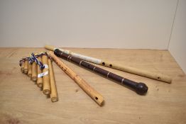 A trio of bamboo wind instruments including a set of pan pipes and two recorders and a bagpipe
