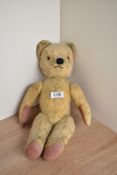 A mid 20th century straw filled yellow plush Teddy Bear having plastic eyes, stitched nose and mouth