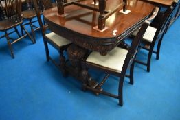 An early 20th Century draw leaf table and five (four plus one) chairs having heavily carved