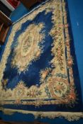 A vintage Chinese carpet square having blue ground with floral pattern and fringed edge, approx