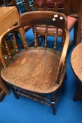 A late 19th or early 20th Century solid seat armchair having turned frame