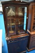 A reproduction Regency display cabinet with double cupboard under, of narrow proportions