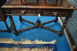 A Victorian oak side table having frieze drawers with mask handles and twist X frame
