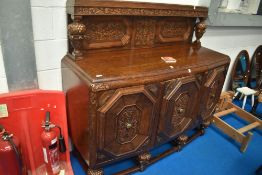 An early 20th Century oak sideboard having heavily carved foliate and vine decoration with cup and