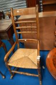 A traditional stained frame rocking chair having spindle back , rush seat and turned frame