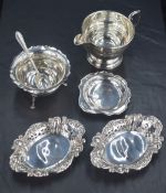 A 1930s silver circular cream jug having a scroll handle and step mounted foot sold along with a