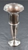 A George V silver fluted vase, having a flared rim with scroll decoration, a central moulded step