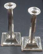 A pair of Edwardian silver column candlesticks, with bead thread to the sconce rim and to the