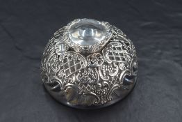 An Edwardian silver mounted glass inkwell, having a hinged cover over the pierced diaper and
