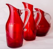 A group of three large Whitefriars glass ruby red 'Sparrow Beak' jugs, each with ribbed clear