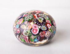 A mid-19th century Clichy scrambled millefiori glass paperweight, of typical domed circular form