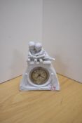 A 20th century Bisque porcelain figural mantel clock, depicting two young children reading a book to