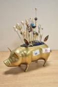 A 20th Century novelty brass pig pin cushion and pins, measuring 20cm long
