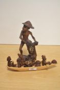 A carved Indian study of a gent in primitive attire and a carved wooden boat with African figures.