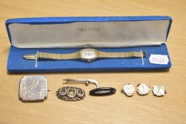 A group of four silver and white metal brooches comprising a silver field hockey stick and ball