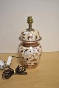 A decorative African pottery table lamp, of lidded urn form, hand decorated with repeating floral